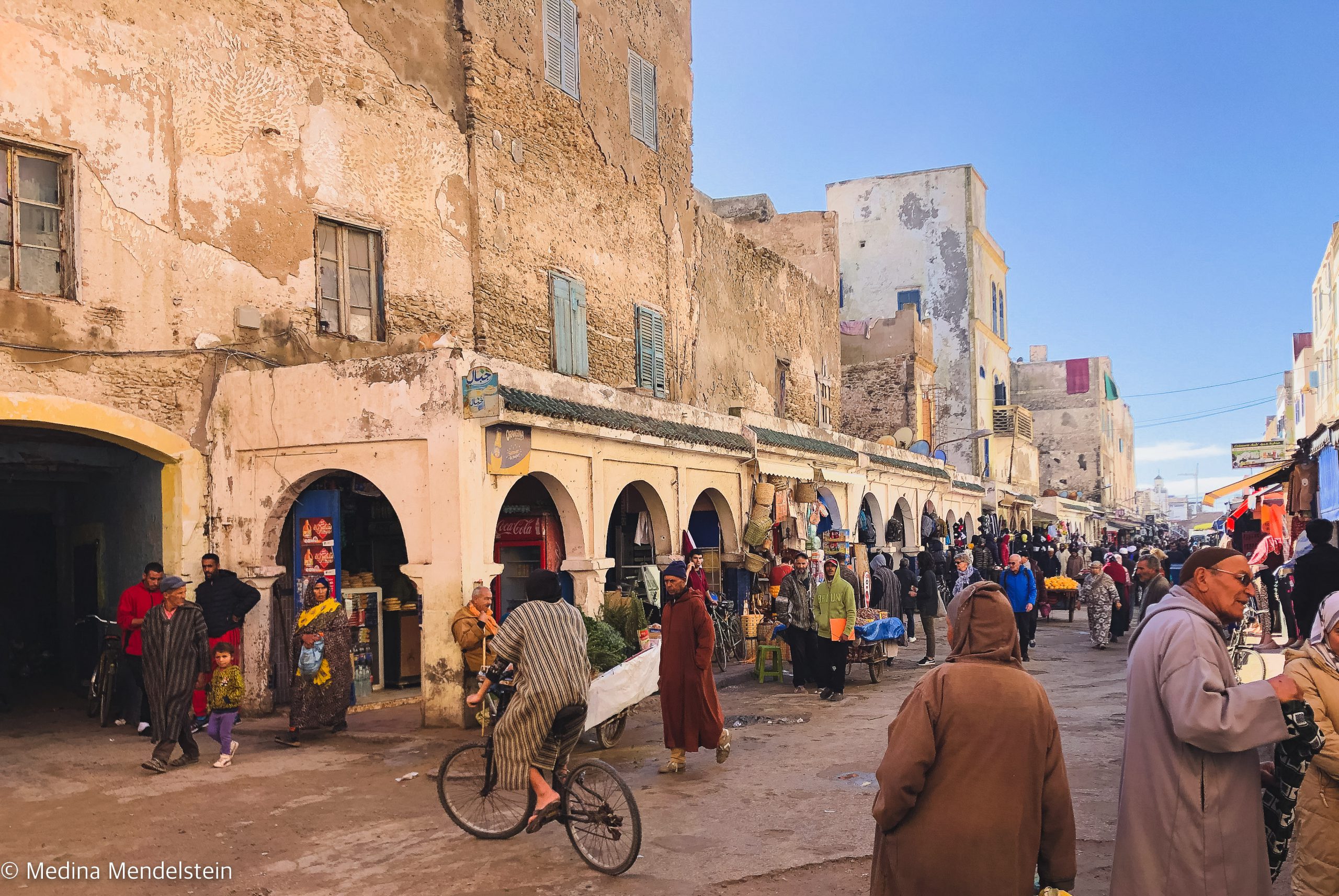 Fotografie aus Marokko, Essaouira: Einkaufsstraße mit vielen Menschen. An den Straßenrändern sind Verkaufsläden.