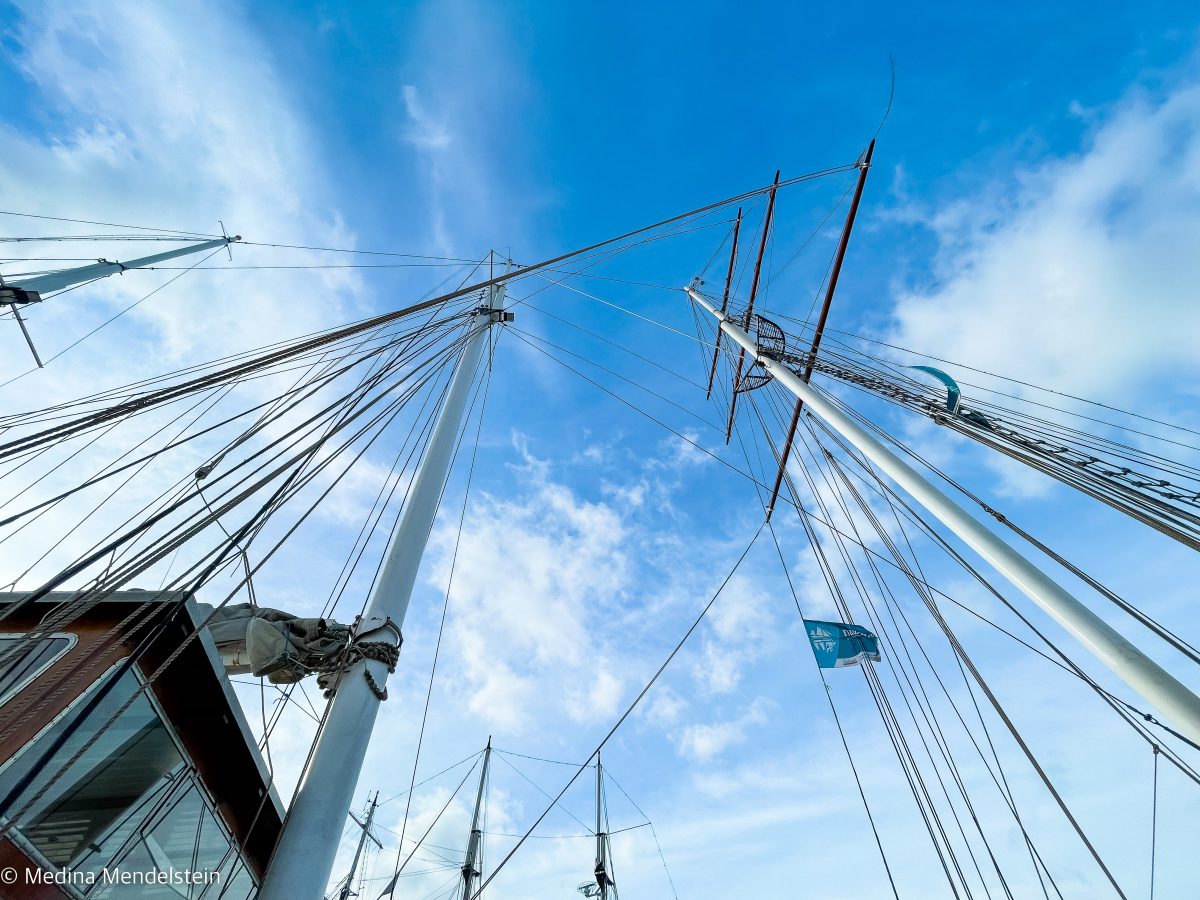 Fotografie während einer Flusskreuzfahrt in den Niederlanden, Lelystad. Die Masten mehrerer Segelschiffe sind von untern in Richtung Himmel fotografiert.